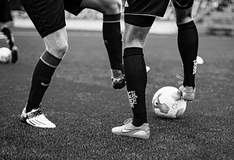 Fötter av fotbollsspelare dribblar en fotboll.